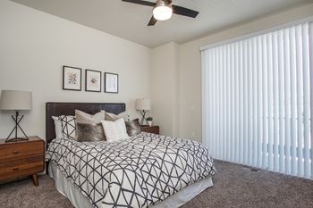 A bedroom with a bed, two lamps, and a ceiling fan.